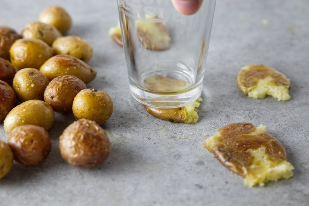 smashing cooked baby potatoes with glass