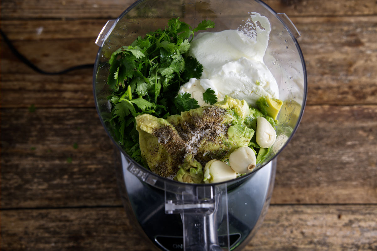 Ingredients for avocado crema in a food processor.