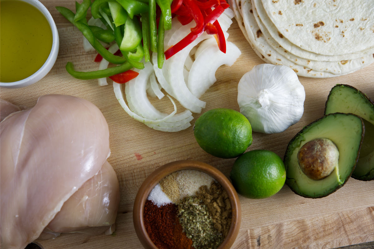 Ingredients for Blackston Fajitas including chicken breast, onions, bell peppers, spices, lime, avocado, garlic, oil, and tortillas.