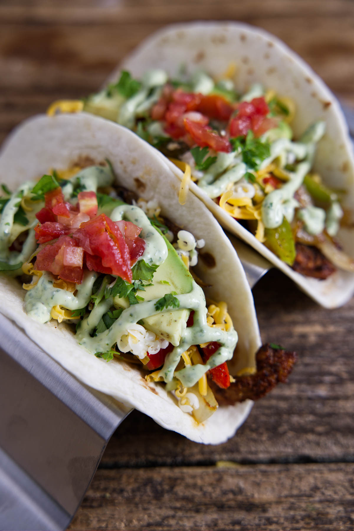 Delicious Blackstone Fajitas served in tortillas, garnished with avocado crema and vibrant bell peppers.