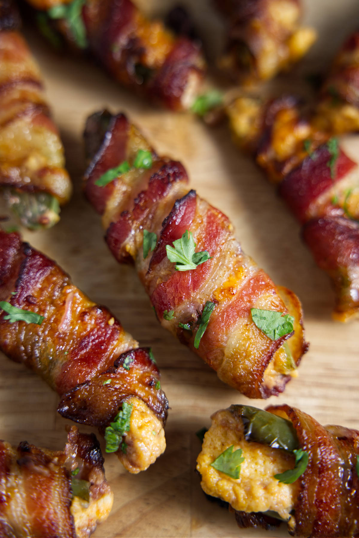 Several bacon wrapped jalapeño poppers on a cutting board.