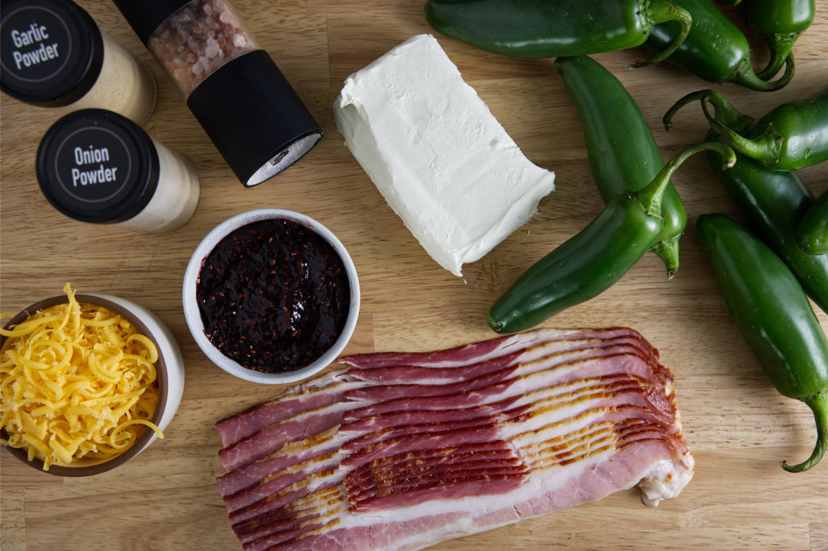 Ingredients for bacon wrapped jalapeño poppers in the air air fryer. Jalapeños, bacon, cream cheese, cheddar cheese, seasoning, and raspberry jam.