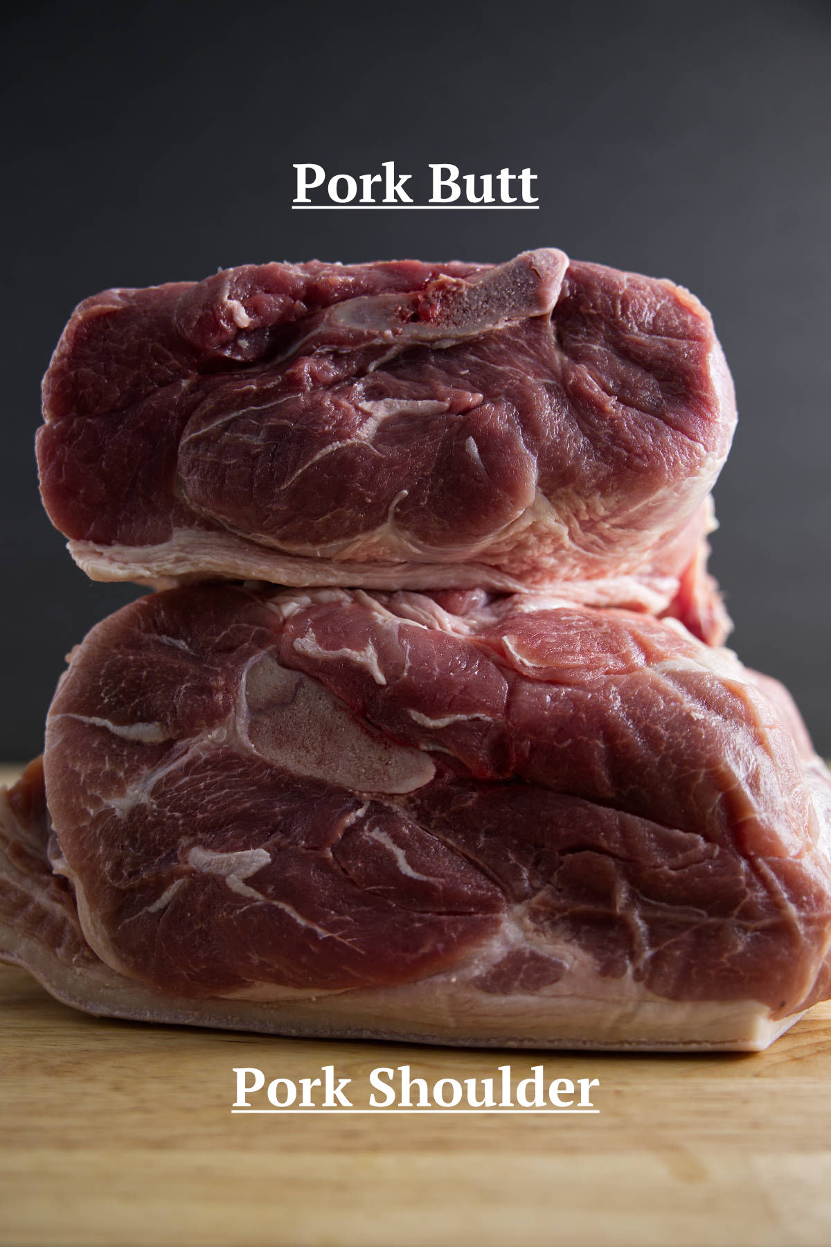 Pork shoulder (picnic shoulder) and pork butt (Boston butt) stacked on a butcher block.