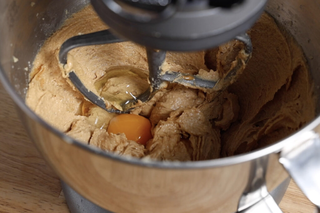 Mixing eggs and vanilla into cookie dough in stand mixer.