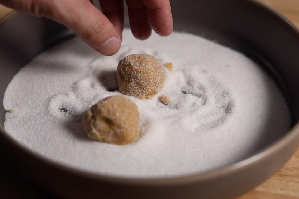 Rolling cookies in sugar.