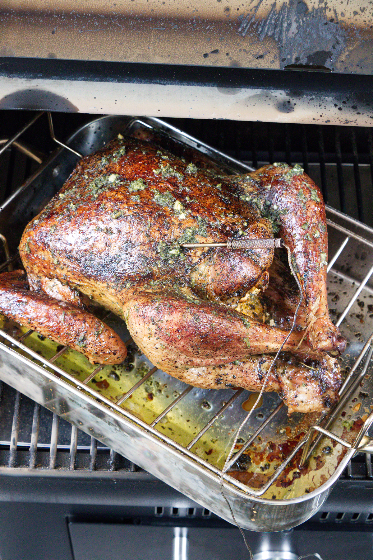 Dry brine smoked turkey on the Traeger grill, smoking in a roasting pan on the grill.