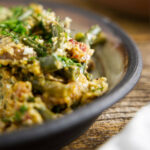 Close up of smoked green bean casserole on a plate, loaded with bacon and mushrooms.