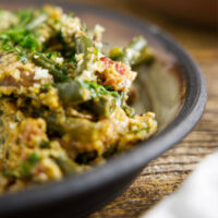 Close up of smoked green bean casserole on a plate, loaded with bacon and mushrooms.