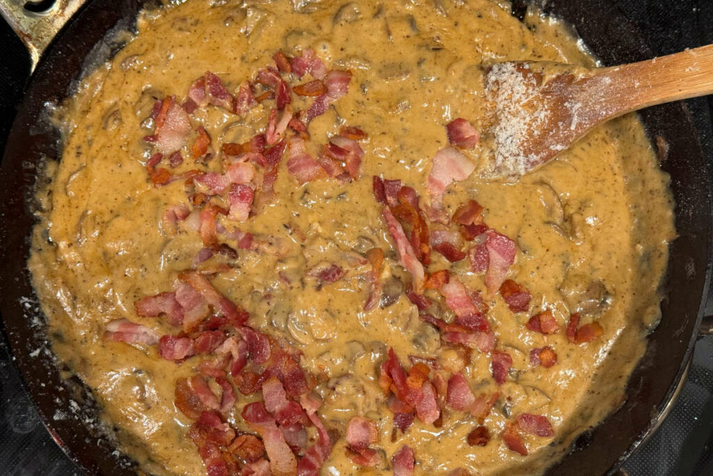 Adding bacon to the fry pan with the sauce for the green bean casserole.