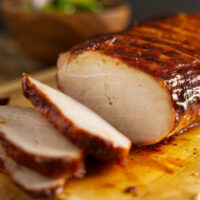 How to BBQ pork loin, whole pork loin sliced on cutting board.