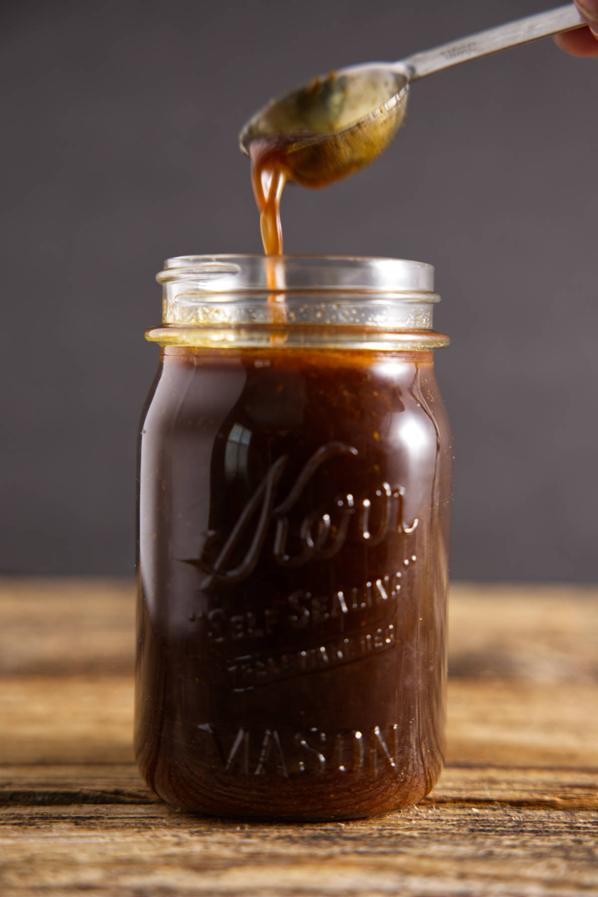 Pouring pork loin marinade for smoker into glass Mason jar.