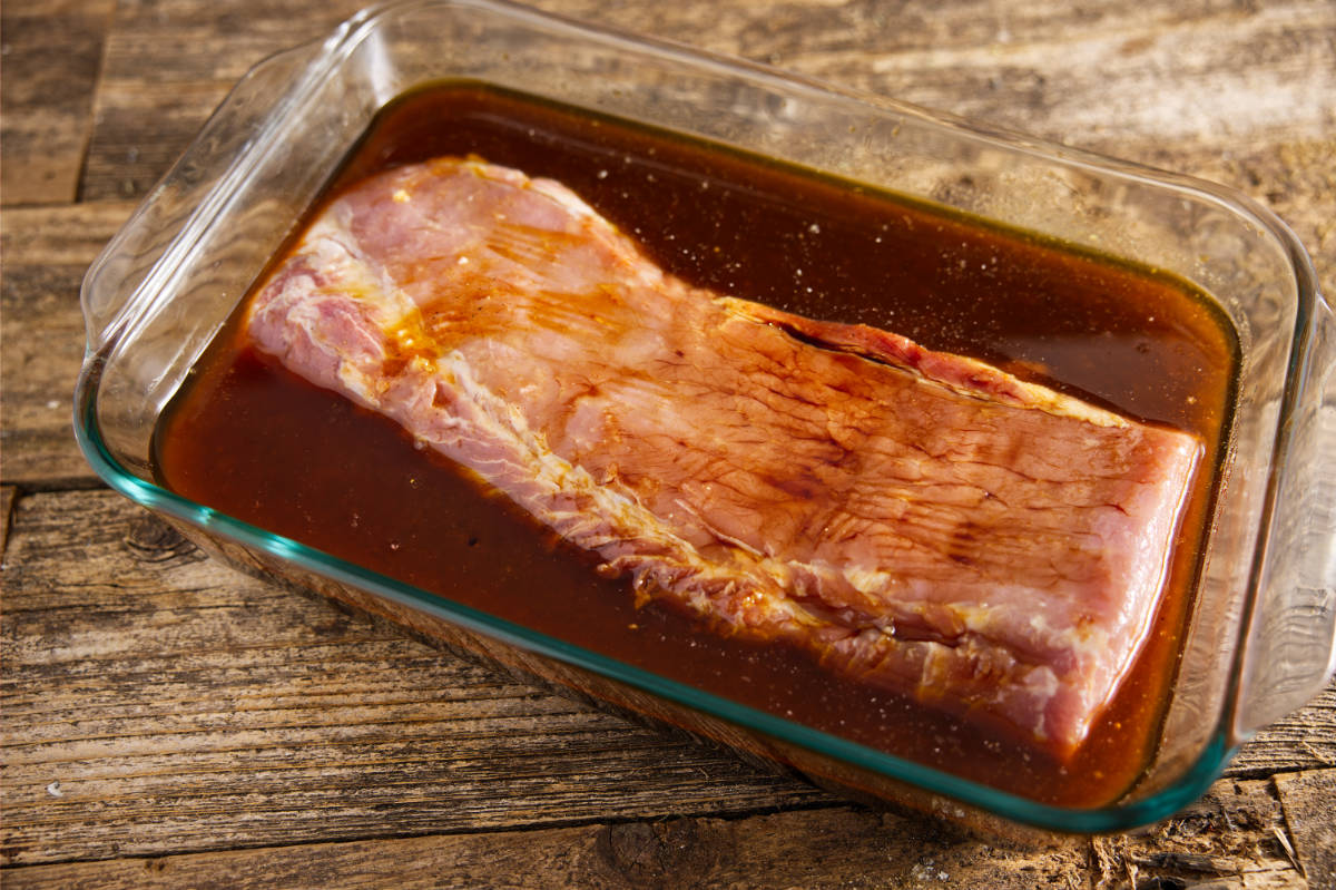 Pork loin soaking in marinade in large Pyrex.