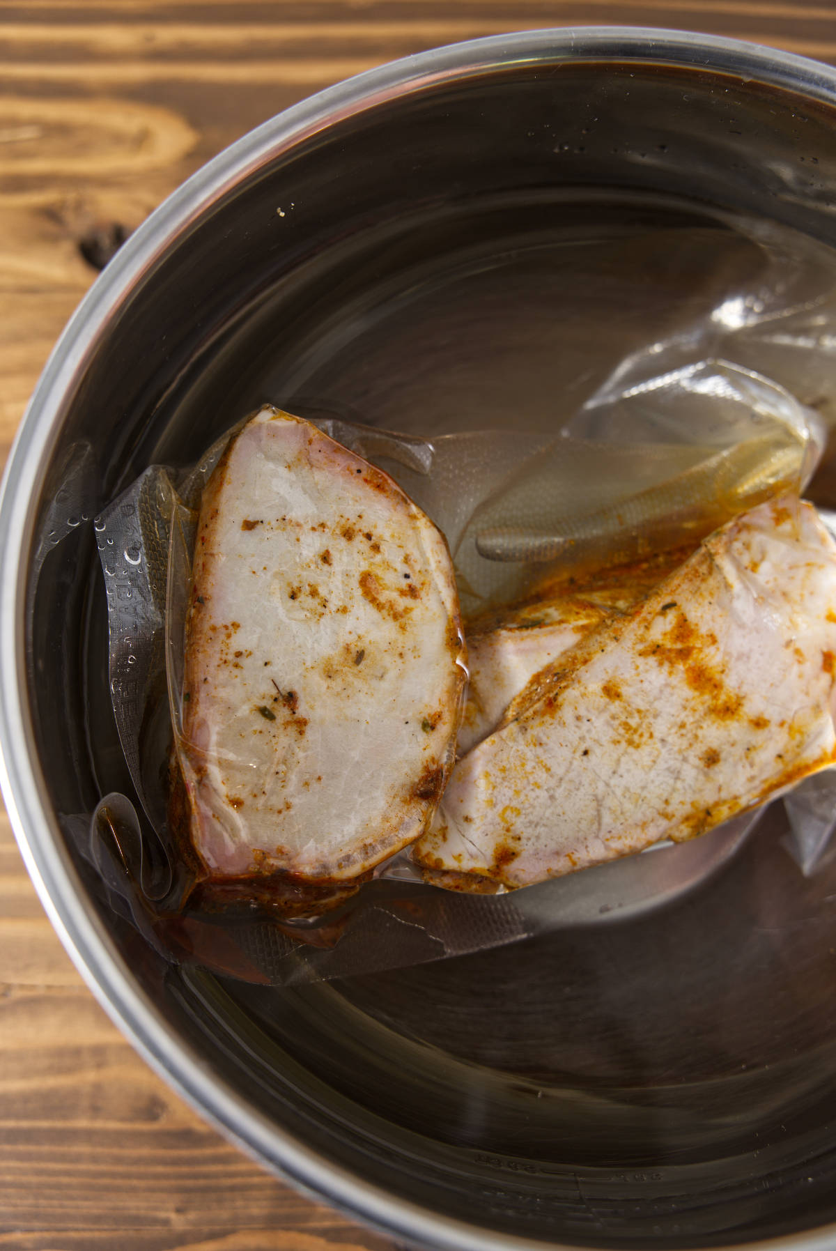 Sliced pork loin in vacuum sealed bag thawing in a water bath.