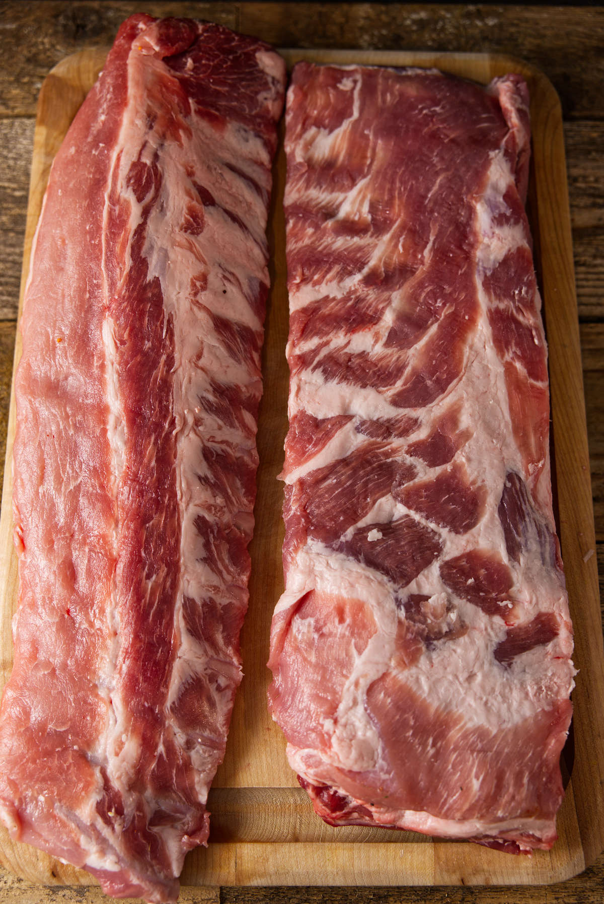 Pork loin back ribs and st. louis style spare ribs on cutting board.