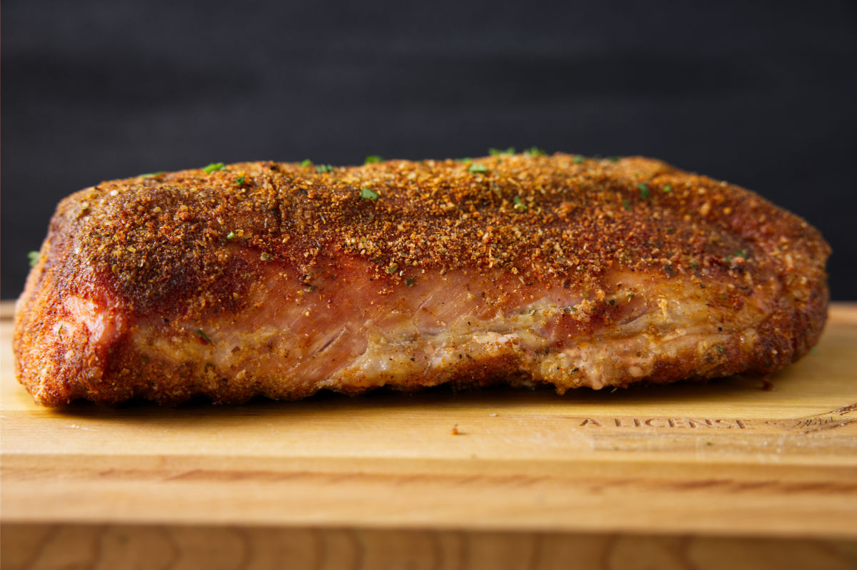 Close up of smoked pork loin resting on a cutting board.