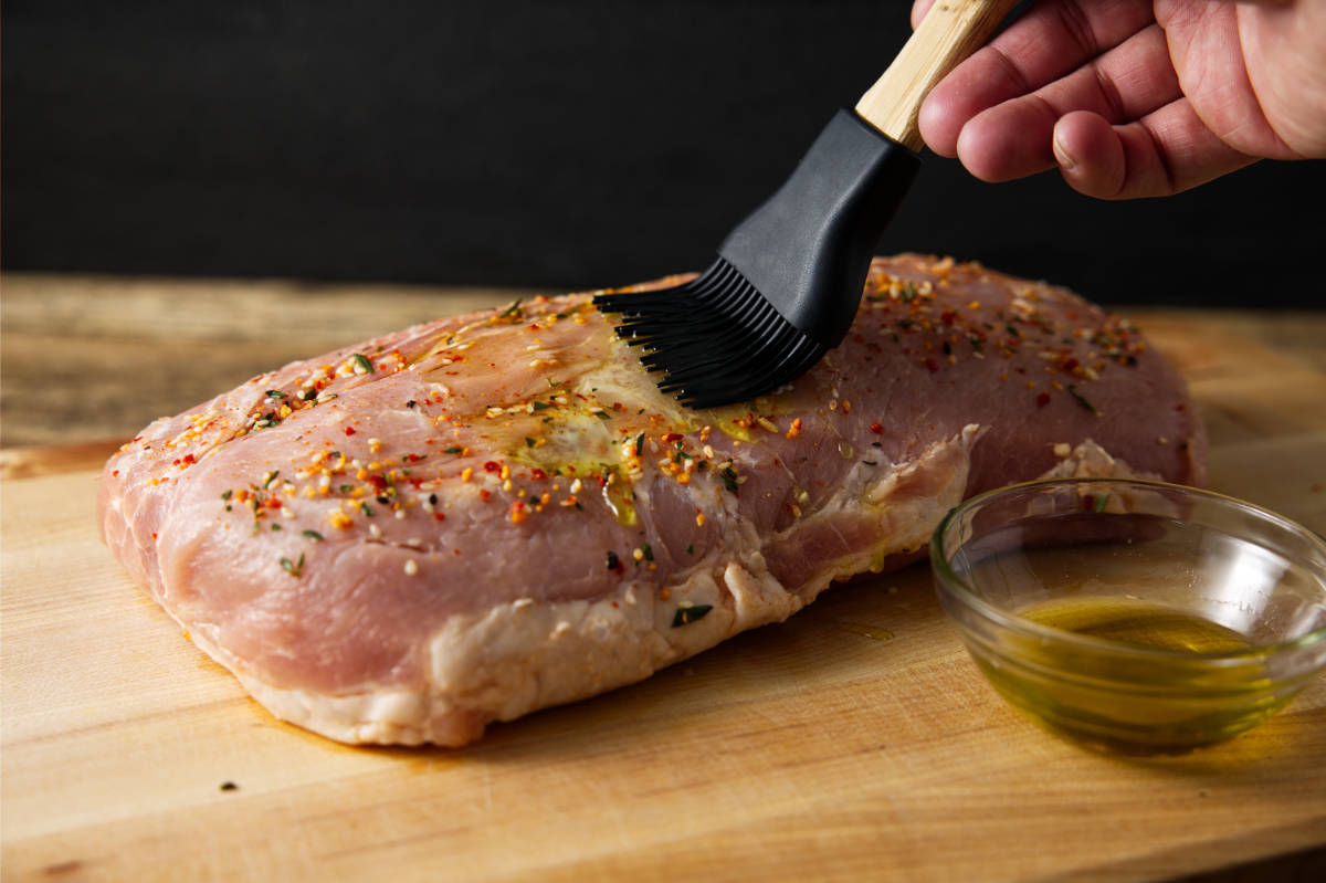 Brushing a pork loin with olive oil.