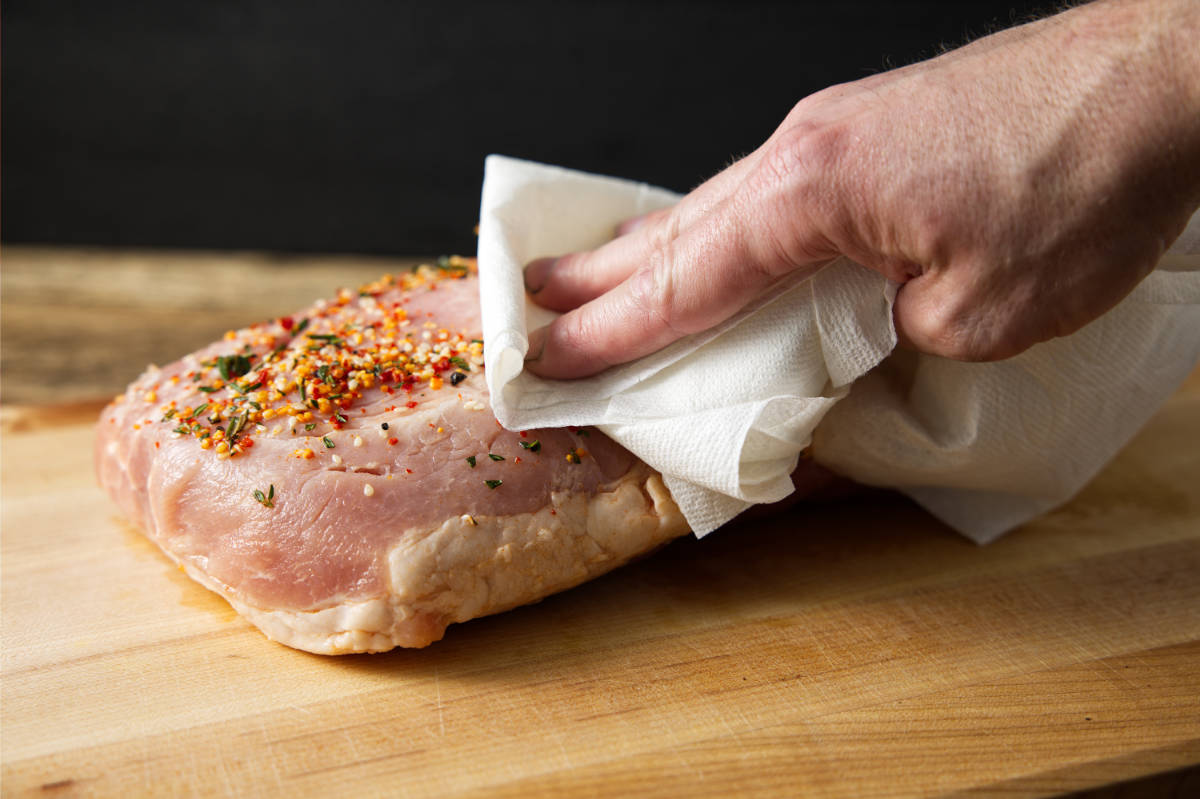 Patting pork loin dry with a paper towel.