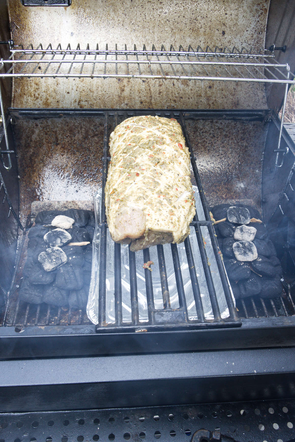 Pork loin smoking on the charcoal grill using the parallel or 2-zone method with a water pan.