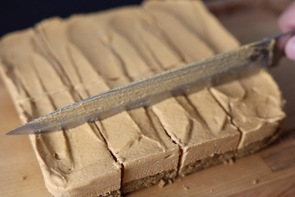 Slicing pumpkin cheesecake bars into squares.