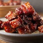 Close up of pork burnt ends stacked on a plate.