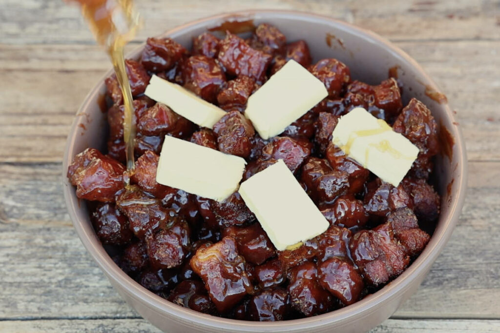 Adding honey to burnt ends in pan.