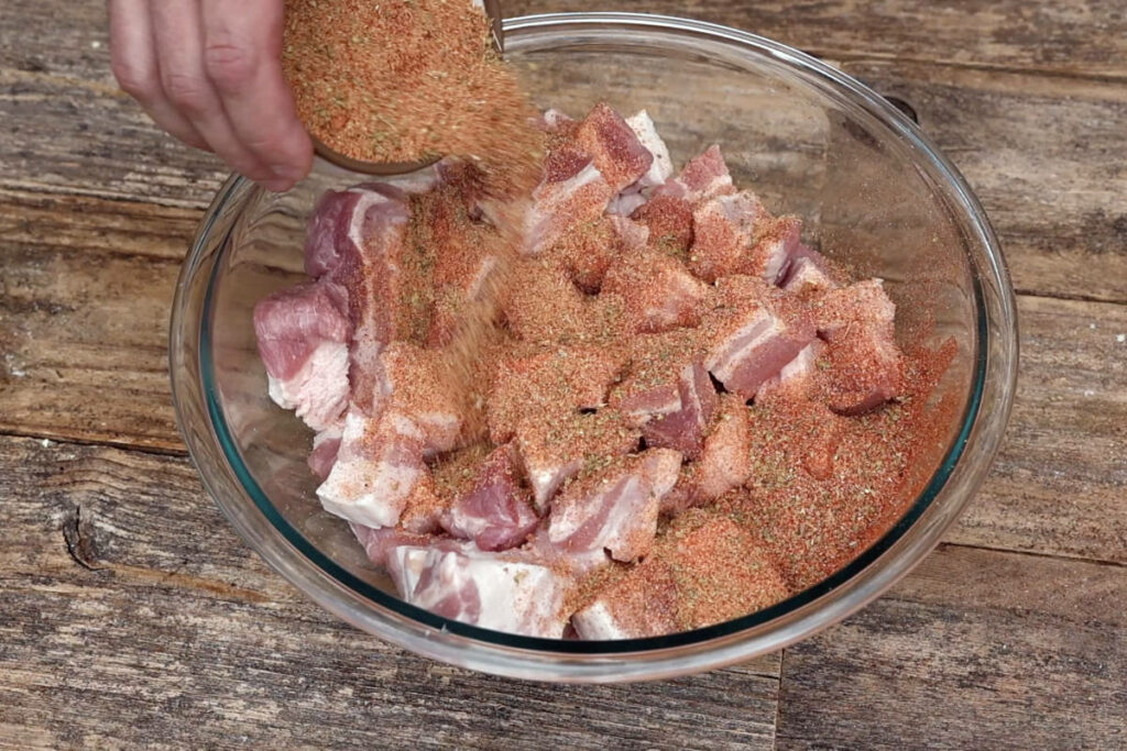 Pouring seasoning over cubed pork belly.