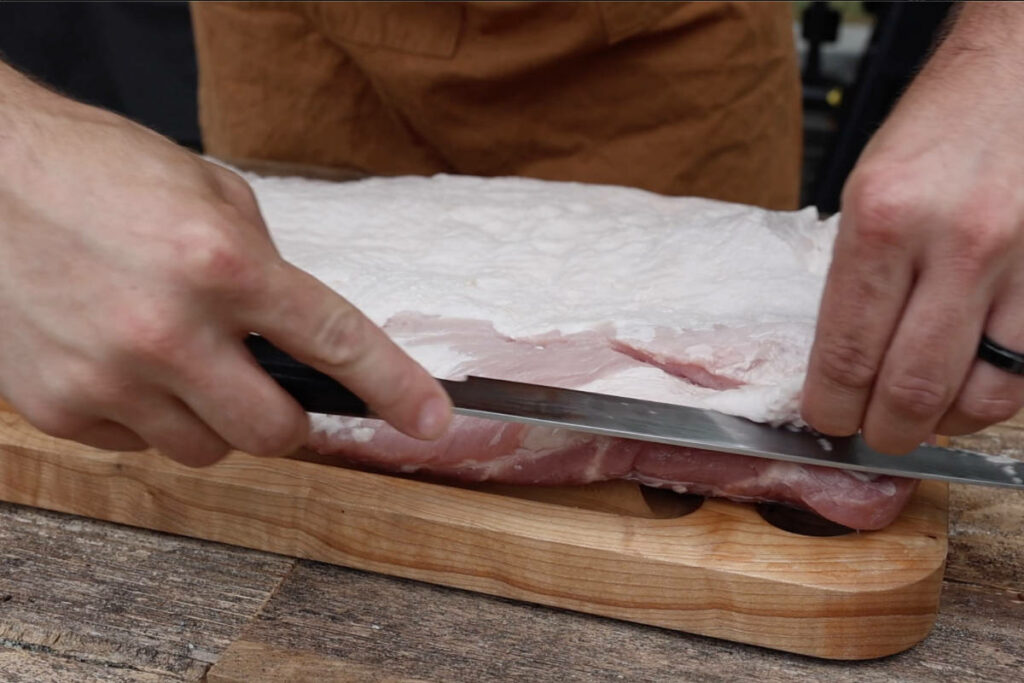 Trimming excess fat from the pork belly.