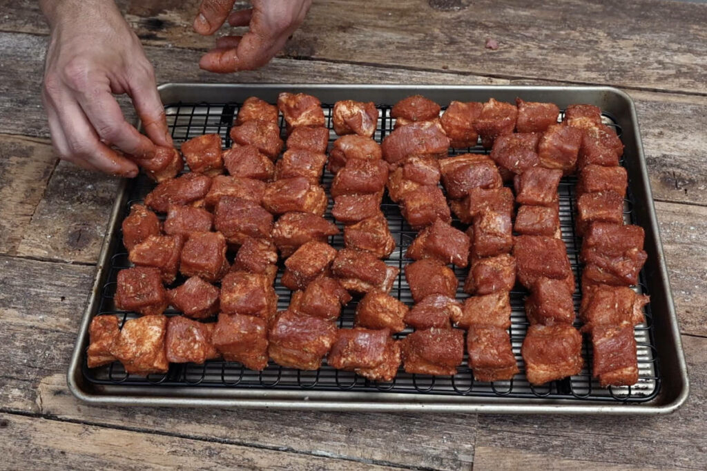 Arranging cubes of pork belly on a wire rack.