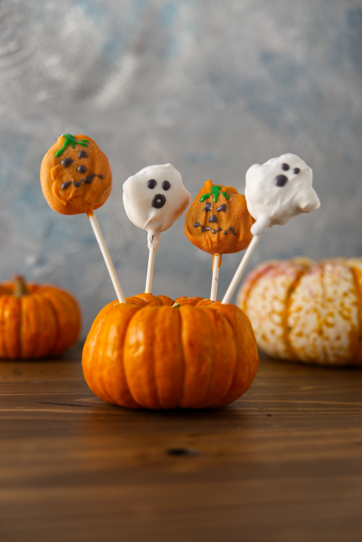 Halloween cake pops, decorated and on display, propped up on display in a pumpkin.