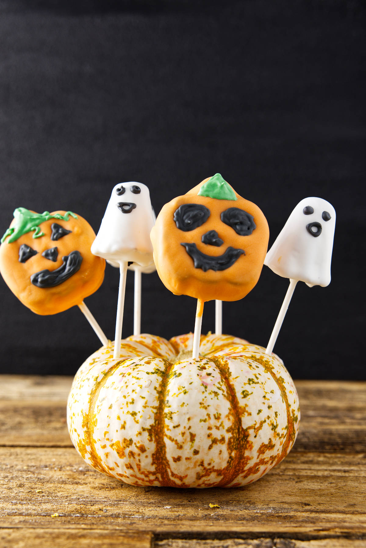 Halloween cake pops sticking out of a pumpkin.