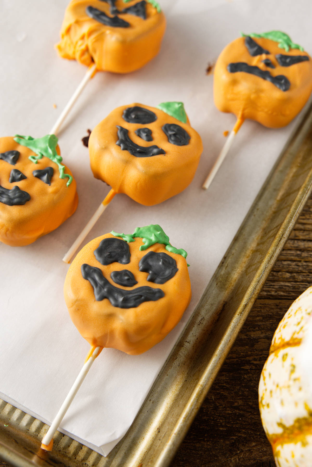 Jack-o'-lantern cake pops on cookie sheet.