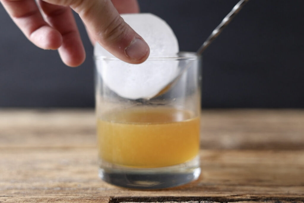 Adding sphere ice to cocktail glass.