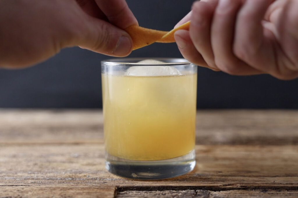 Expressing orange peel over cocktail.