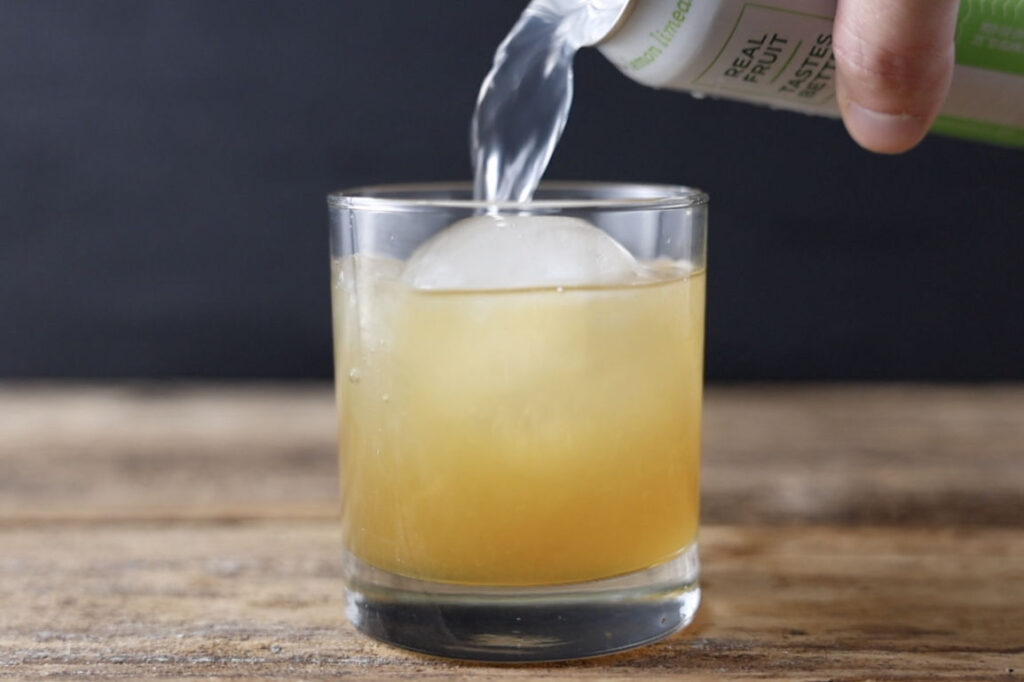 Pouring seltzer water in cocktail.