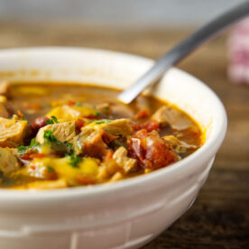 Close up of bowl of leftover turkey chili, loaded with chunks of tomatoes and turkey.