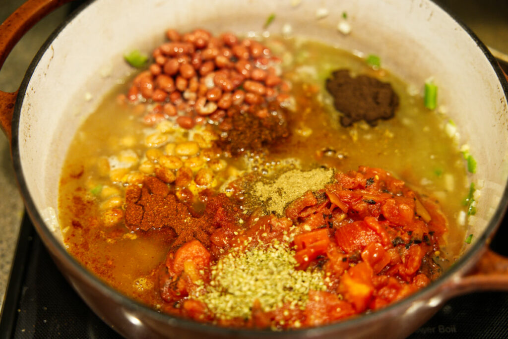 All the ingredients for a turkey chili in a Dutch oven, ready to be mixed together.