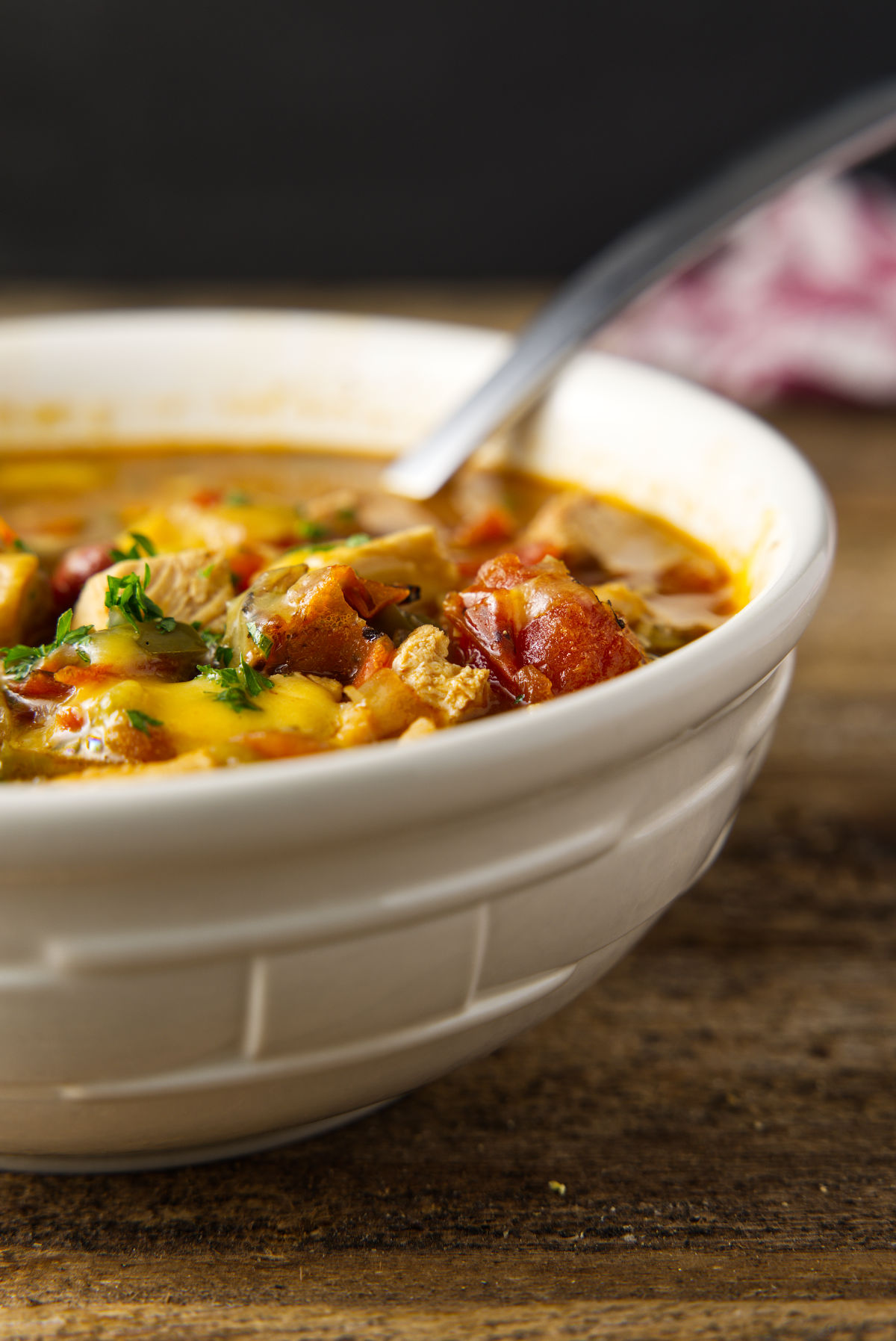 Bowl of leftover turkey chili with melted cheese and parsley on top.