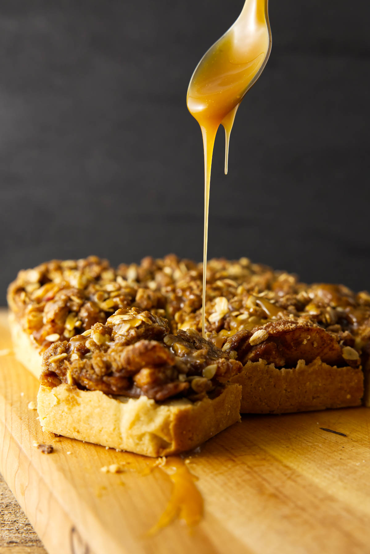 Drizzle of a salted caramel sauce over square slices of apple crisp bars.