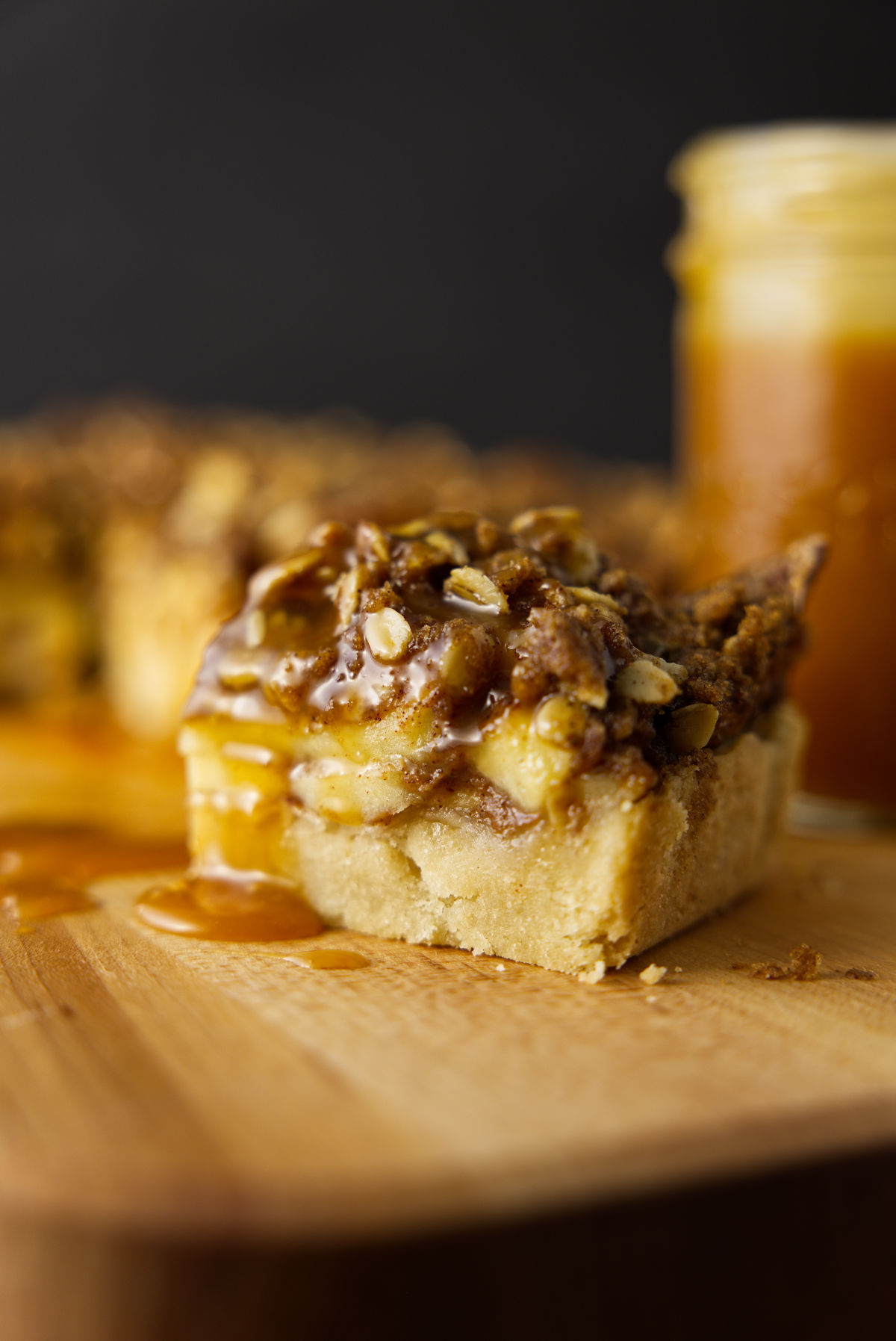 A slice of apple bar with a crispy oat streusel on top and a drizzle of caramel sauce.