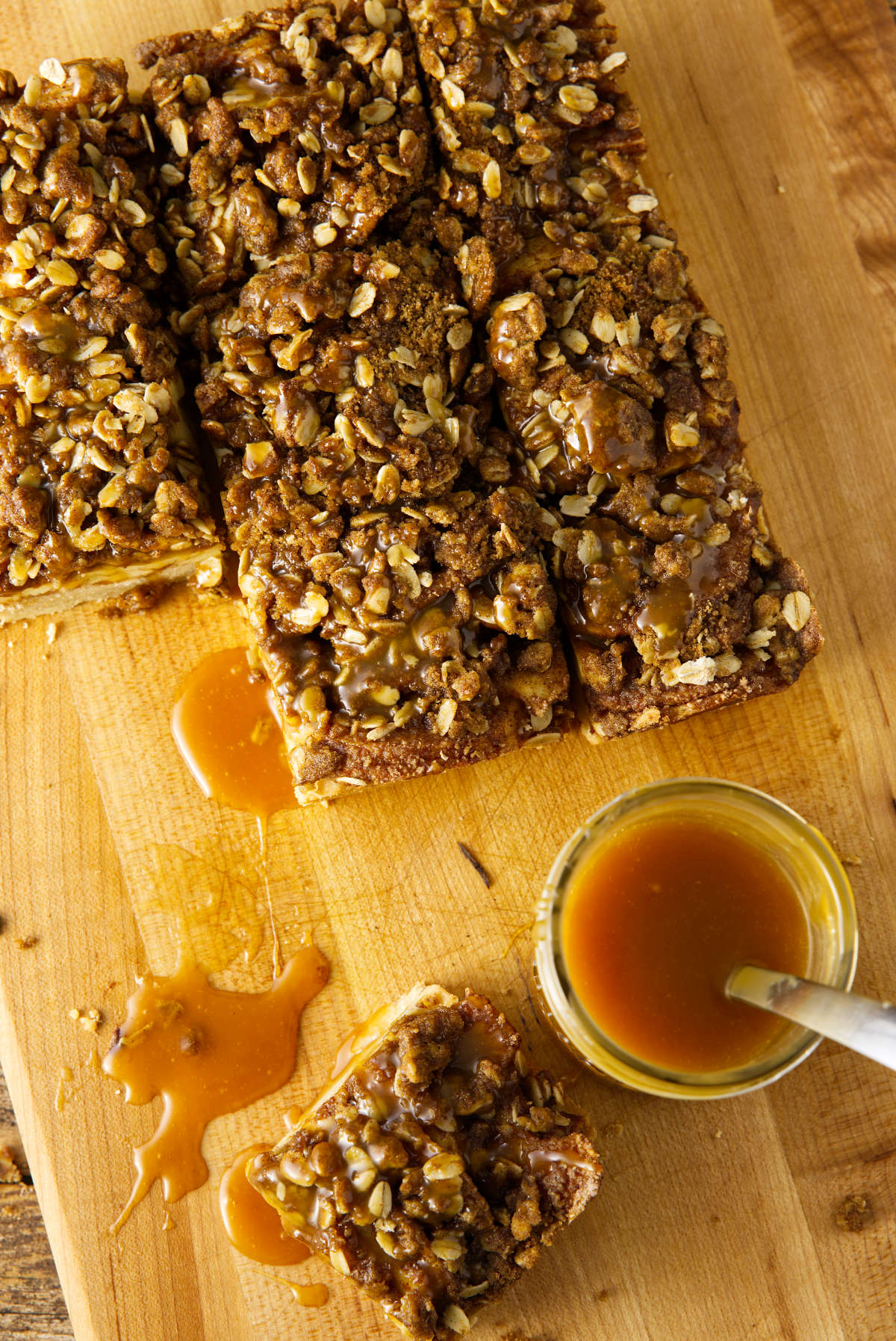 Apple crisp bars with oat streusel on top and a salted caramel sauce in a mason jar.