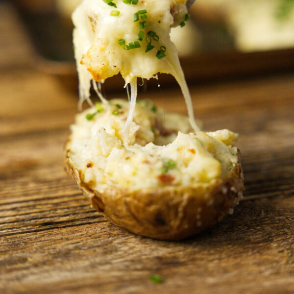 Fork scooping a bite of smoked twice baked potato with a gooey cheese pull.