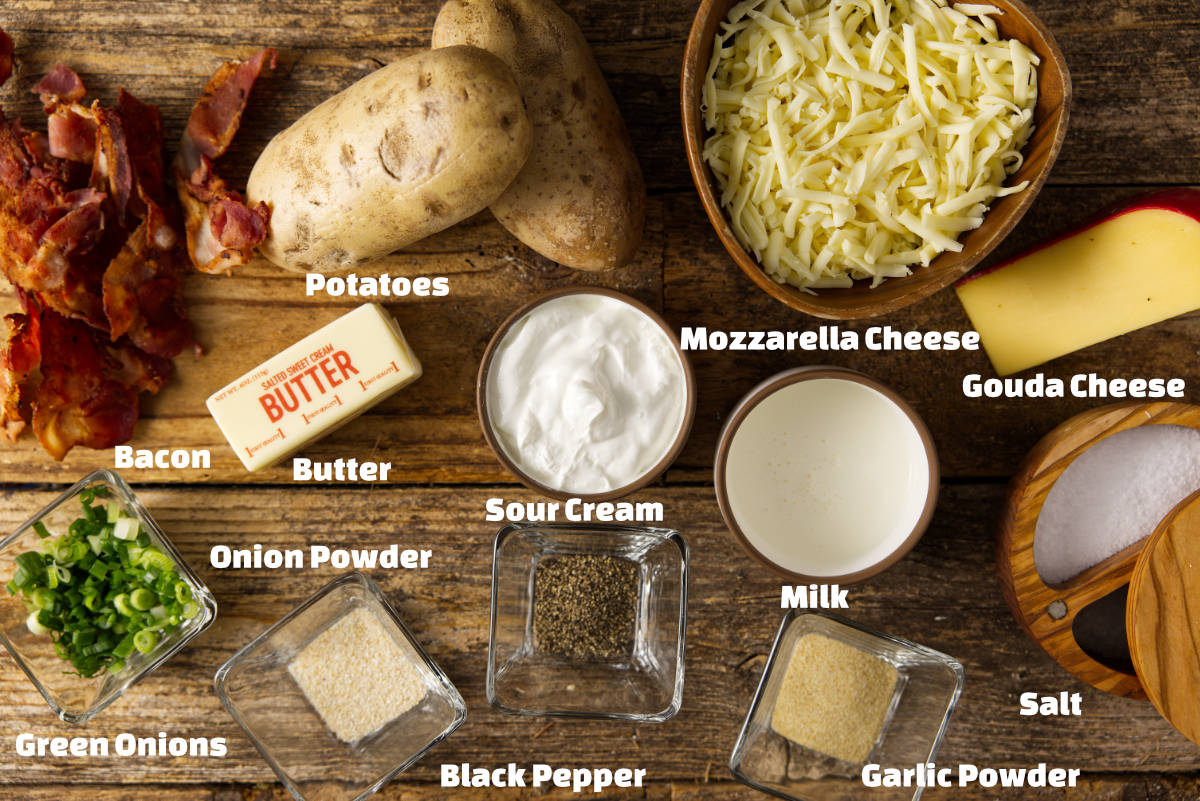 Ingredients for smoked twice baked potatoes all laid out on a rustic wooden background.