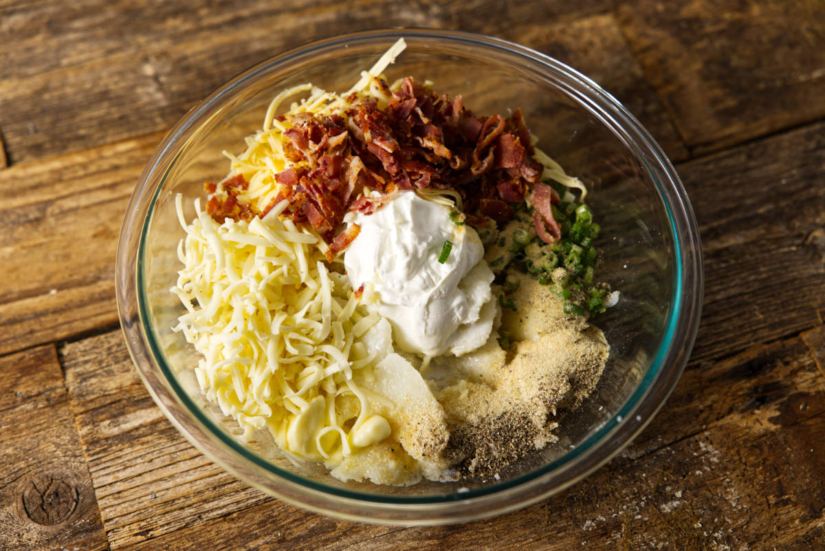 Ingredients for twice baked potatoes in a large glass mixing bowl.