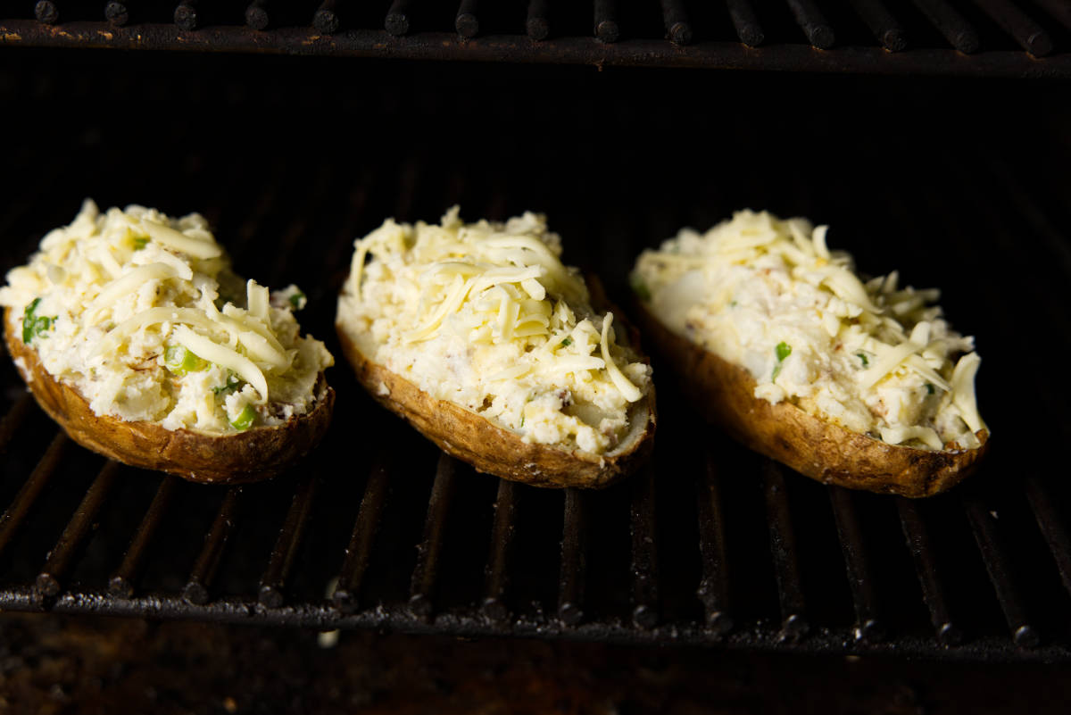 Filled potato skins on smoker grates.