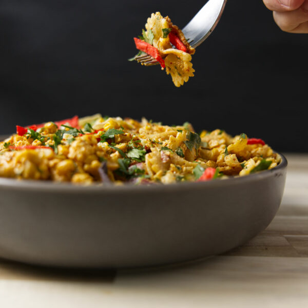 Fork shot with a bite of elote Mexican street corn pasta salad above a heaping full bowl.