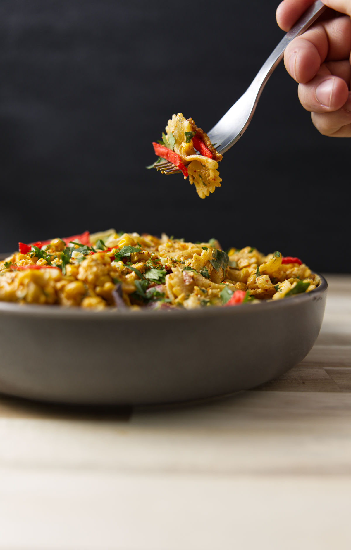Fork shot with a bite of Mexican street corn pasta salad above a heaping full bowl.
