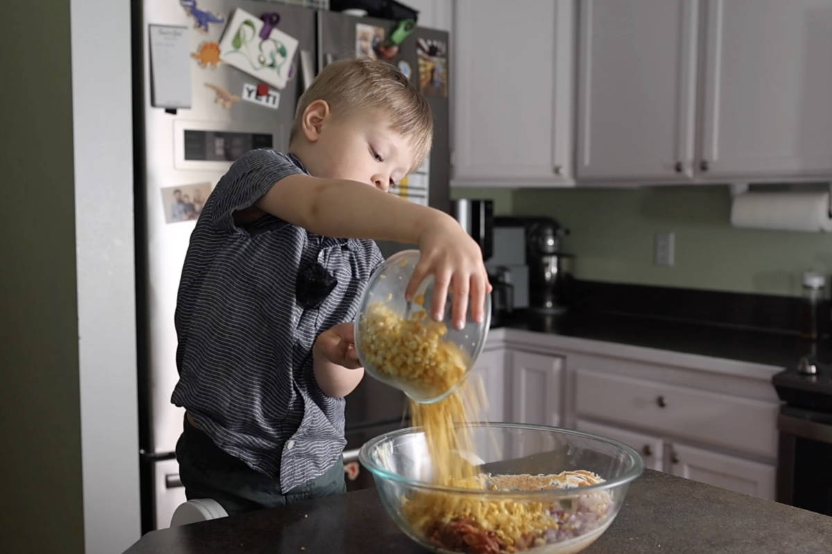 Adding corn into the bowl of street corn pasta salad.
