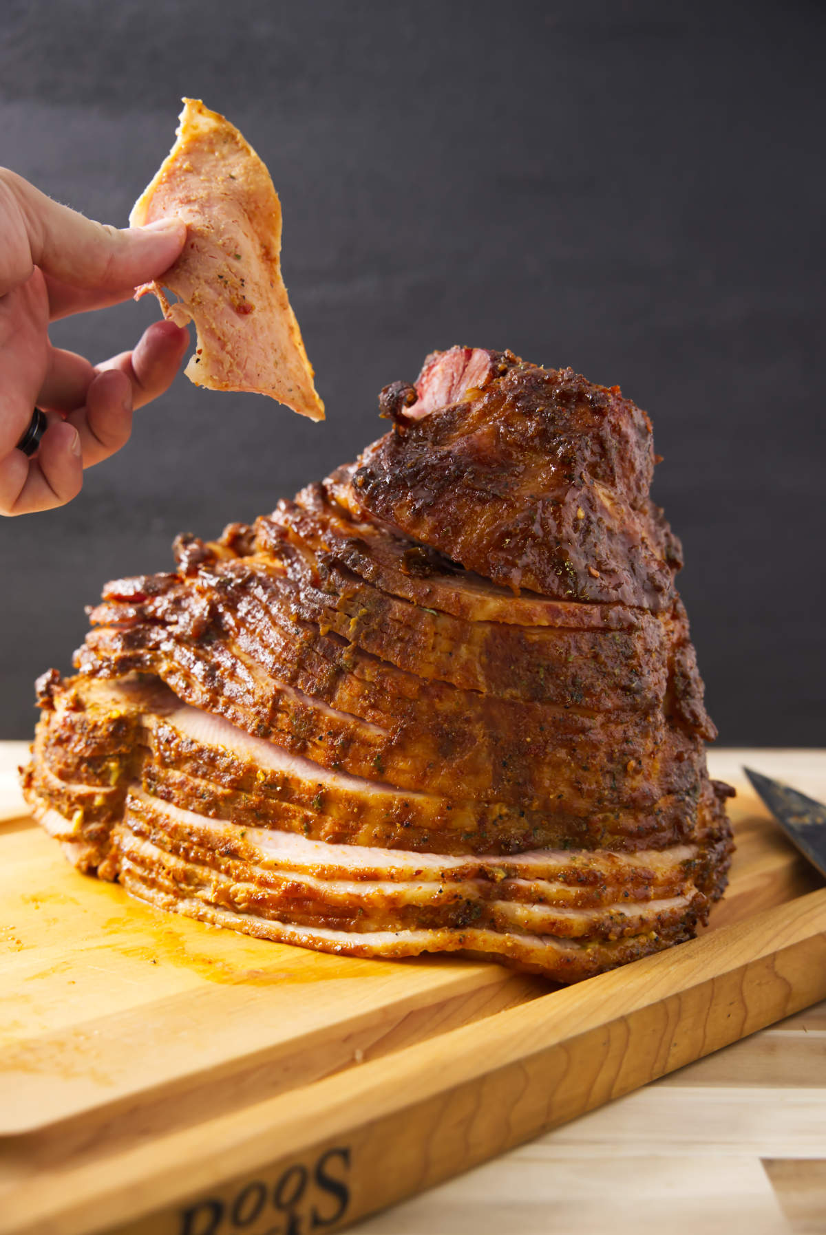 Holding piece of double smoked ham with spiral ham resting on butcher block.