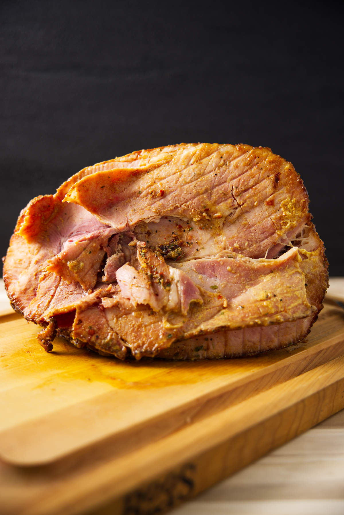 Spiral sliced twice smoked ham resting on butcher block.