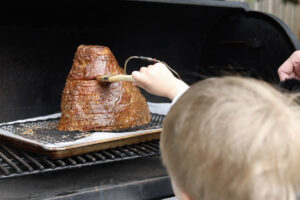 Brushing glaze on the ham while it is on the Traeger.